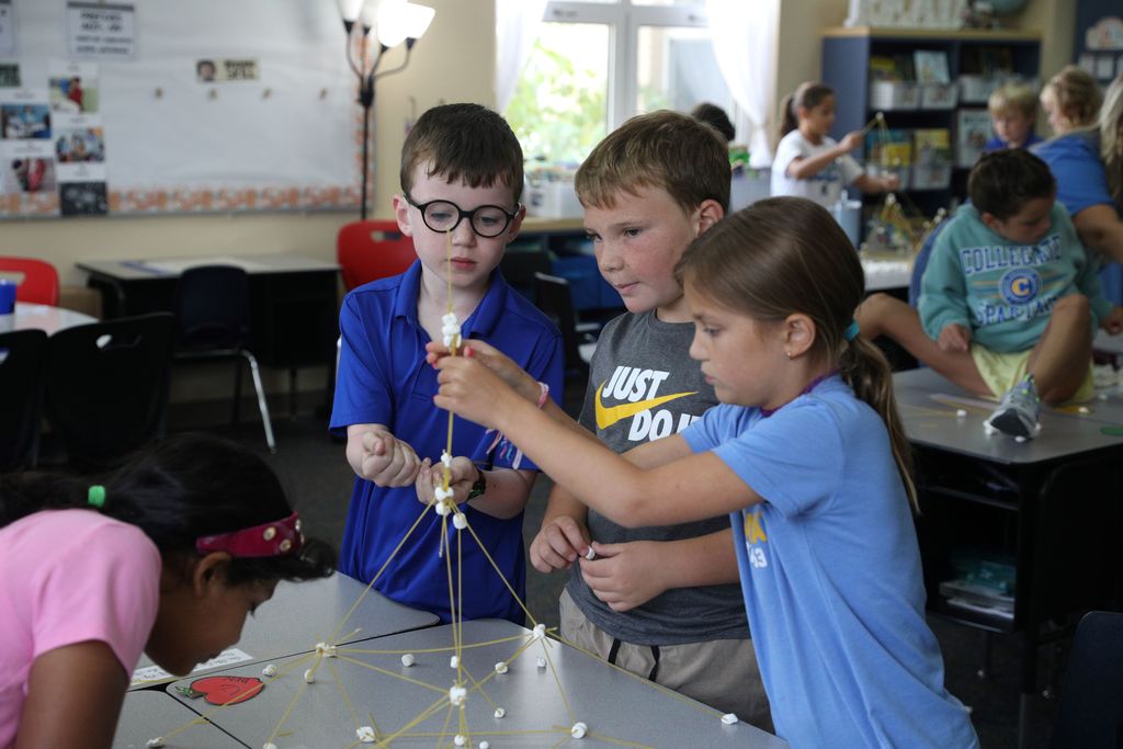 Three students helping build a tower